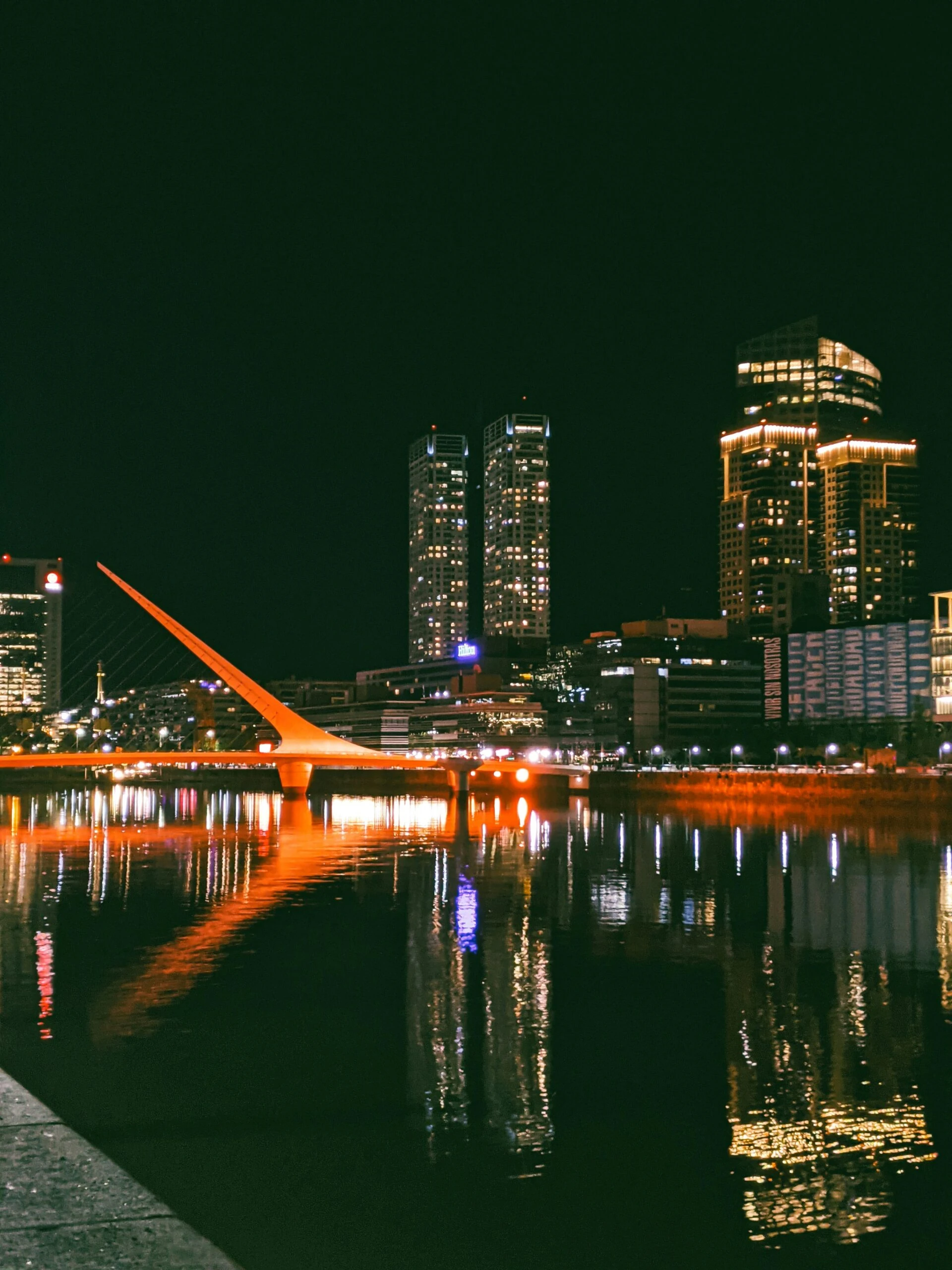 Night view of Puente de la Mujer bridge reflecting on the water in Puerto Madero, Buenos Aires – Buenos Aires City Tour at night